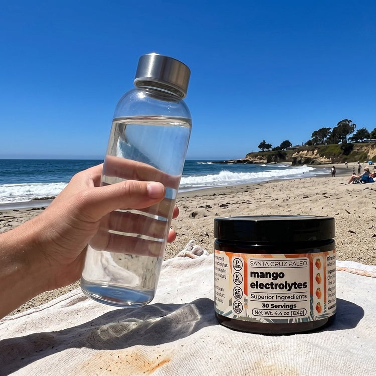 A hand shaking the capped glass bottle, the tub beside it, the beach behind