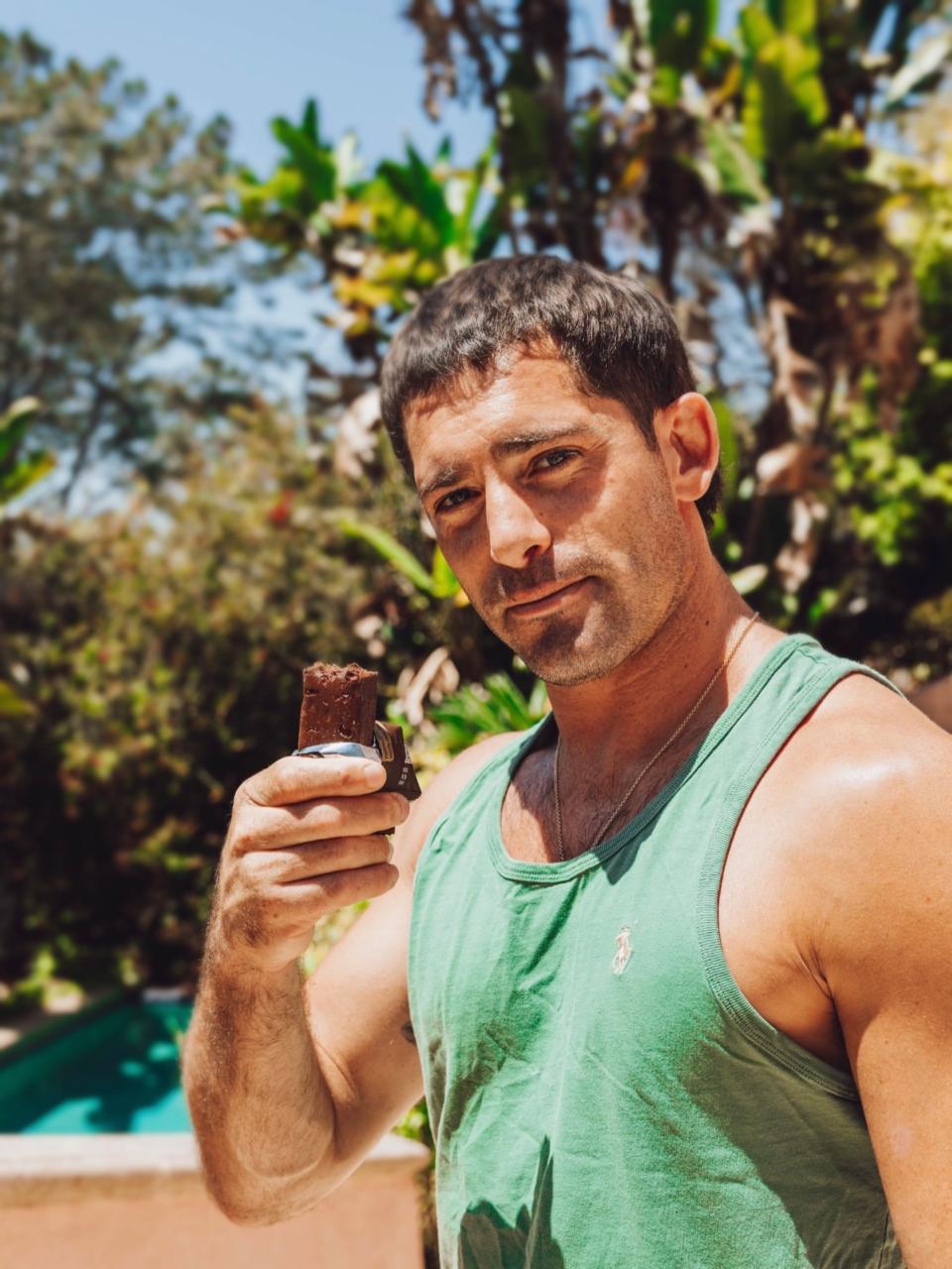 Brendan in a green tank top holding a bar